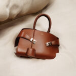 FERRAGAMO_PF24_MAIN_STILL LIFE_W COGNAC HUG BAG_P3